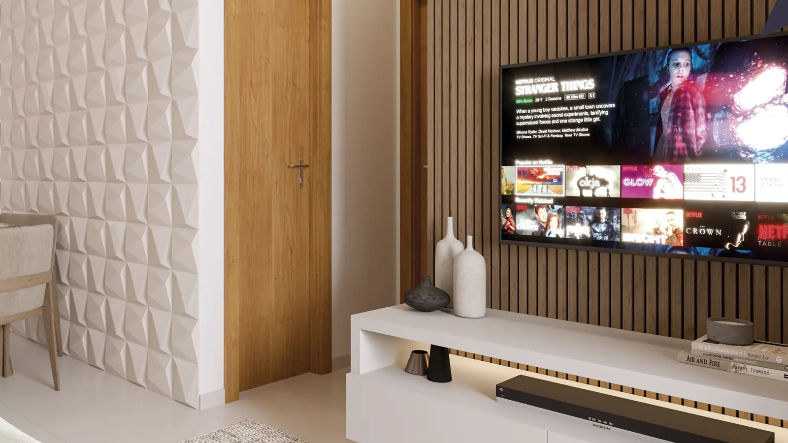 Sala de estar decorada de um apartamento do Gran Village Eusébio III, com painel ripado, televisão e sofá
