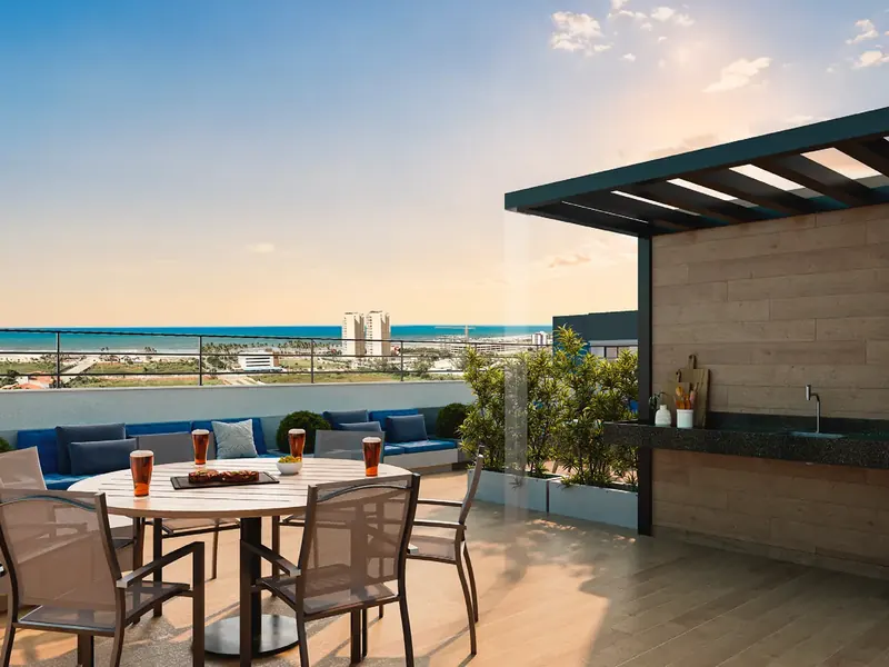 Living externo do rooftop do Hype Condomínio Clube, com mesas, sofás e vista para o mar