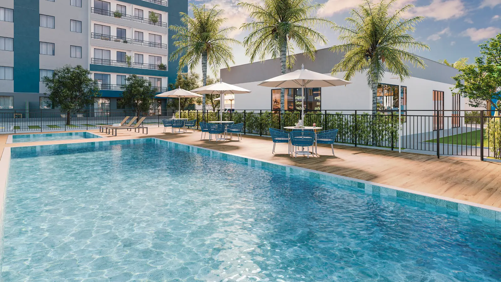 Piscina adulto e piscina infantil do Hype Condomínio Clube, com deck, guarda-sóis e coqueiros, e as torres ao fundo