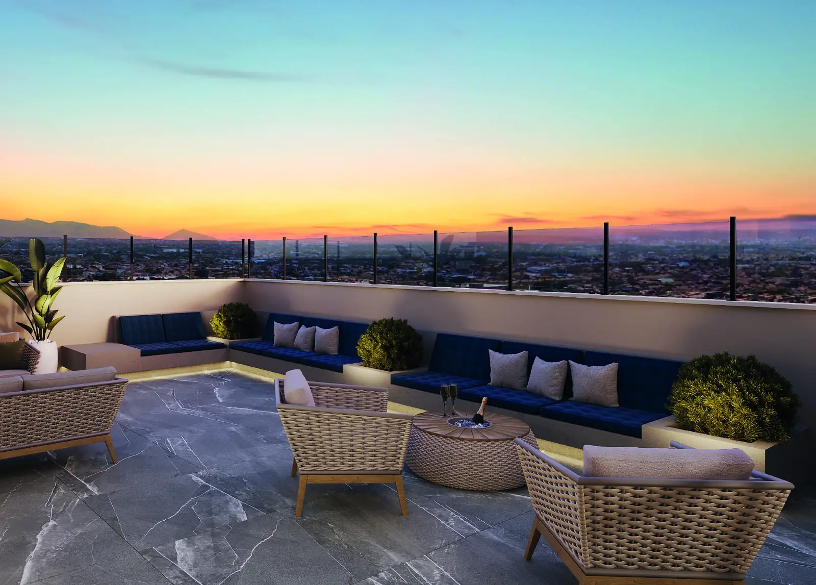 Lounge externo do rooftop do Jóquei Condomínio Clube ao pôr do sol, com sofás em L, poltronas e vista da cidade