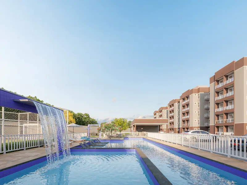 Piscina com cascata do Village Monet, com os blocos de apartamentos ao fundo