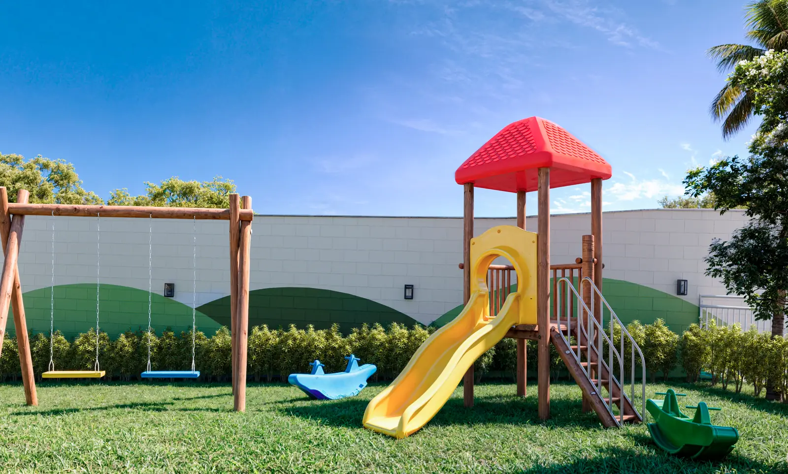 Playground do Vitória Íris com escorregador, balanços e gangorra sobre grama