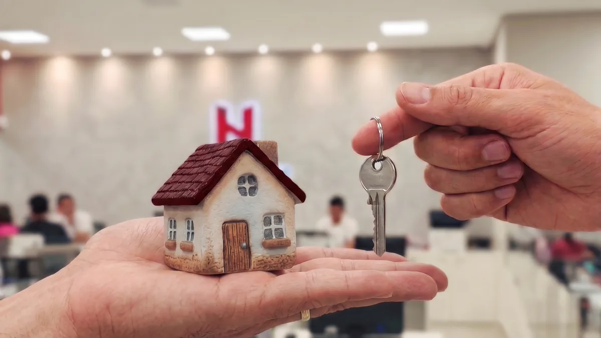 Maos segurando a miniatura de uma casa e a chave, no atendimento da Habitnet